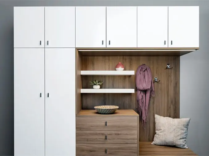 A white mudroom with wooden cabinets and drawers.